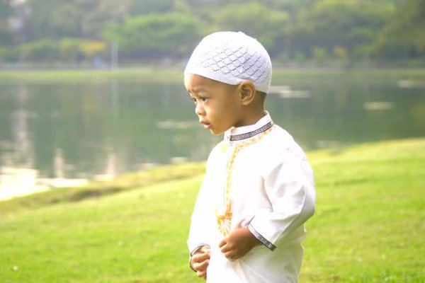 cheerful young boy in traditional garments in public park in mornning